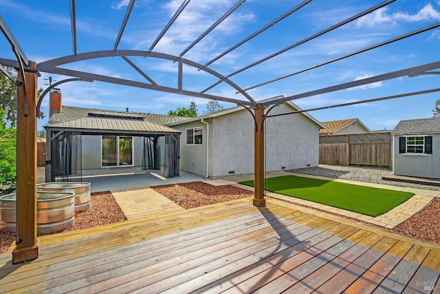 wooden terrace with a gazebo, fence, and a patio area