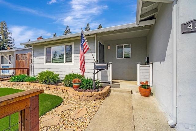 property entrance featuring stucco siding and fence