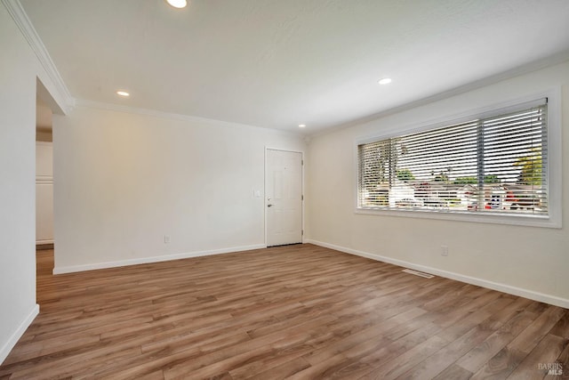 spare room featuring crown molding, recessed lighting, light wood finished floors, and baseboards
