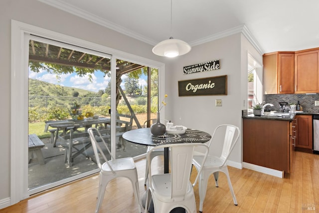 dining space with baseboards, ornamental molding, and light wood finished floors