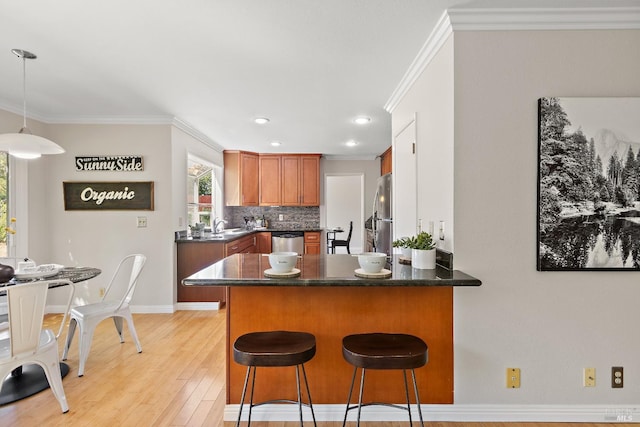 kitchen featuring ornamental molding, appliances with stainless steel finishes, a peninsula, and dark countertops