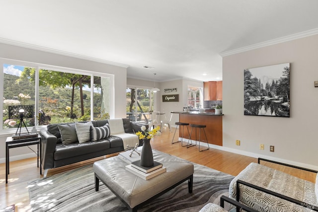 living room with crown molding, baseboards, light wood-style floors, and recessed lighting