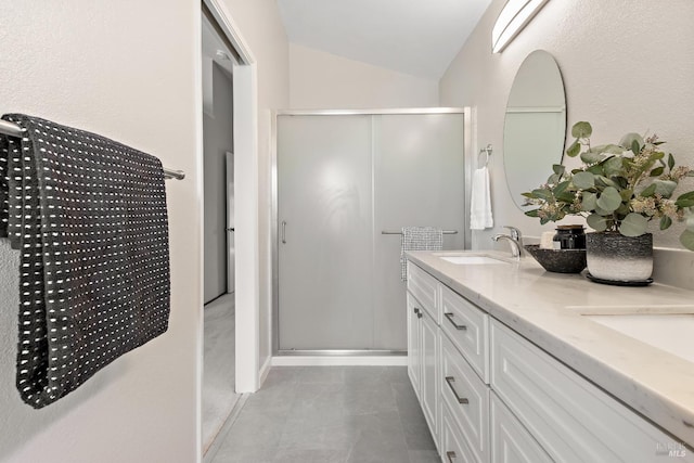 full bath featuring double vanity, vaulted ceiling, a stall shower, a sink, and tile patterned floors