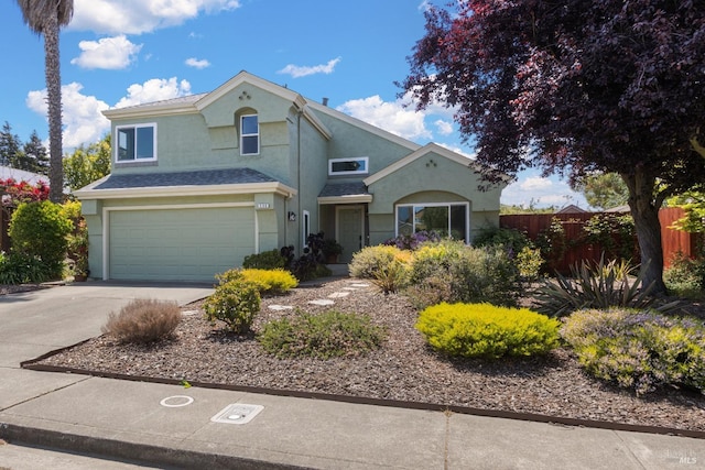 traditional home featuring fence, stucco siding, concrete driveway, and a garage