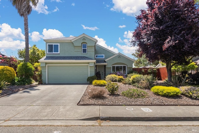 traditional-style house featuring an attached garage, concrete driveway, stucco siding, and fence
