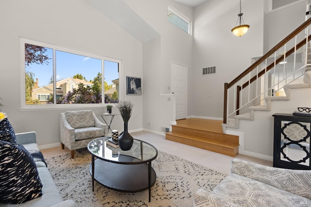 living area with visible vents, stairs, a towering ceiling, and baseboards