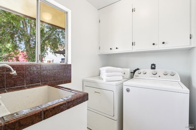 washroom featuring cabinet space, a sink, and washer and clothes dryer