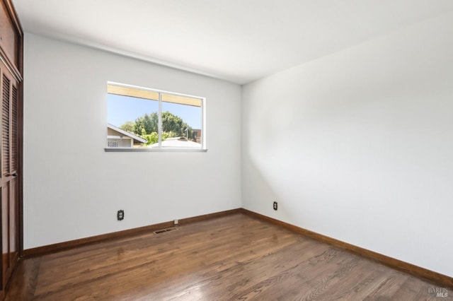 unfurnished bedroom featuring baseboards, a closet, wood finished floors, and visible vents