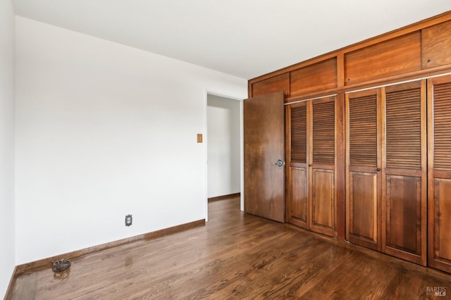 unfurnished bedroom featuring baseboards and dark wood-style floors