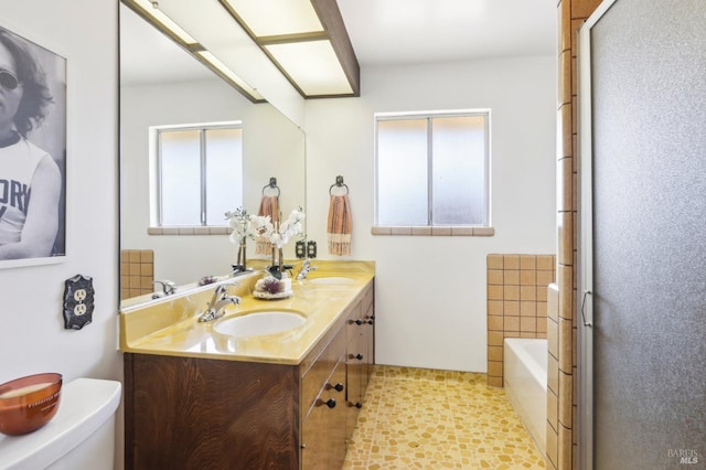 full bathroom featuring a garden tub, a sink, double vanity, and toilet