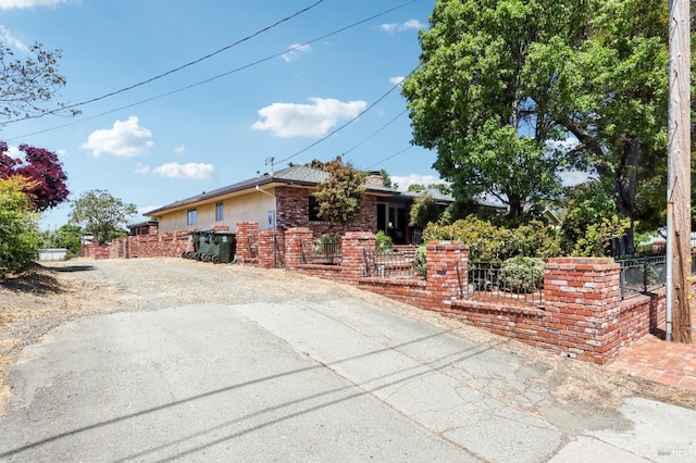 view of side of home with brick siding, fence, driveway, and stucco siding