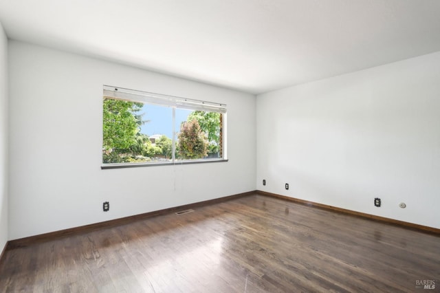 unfurnished room with baseboards, wood finished floors, and visible vents