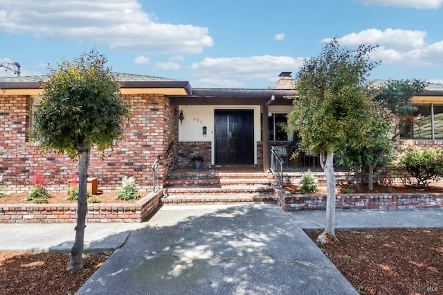 property entrance with a chimney and brick siding