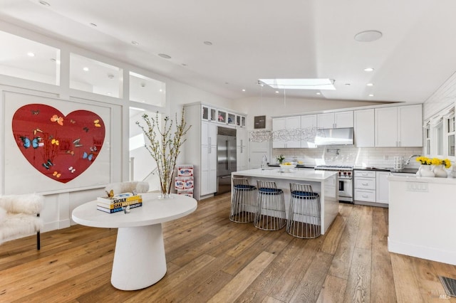 30 Corte Sereno, Greenbrae, CA 94904 - kitchen featuring under cabinet range hood, vaulted ceiling, high quality appliances, white cabinets, and light wood-type flooring