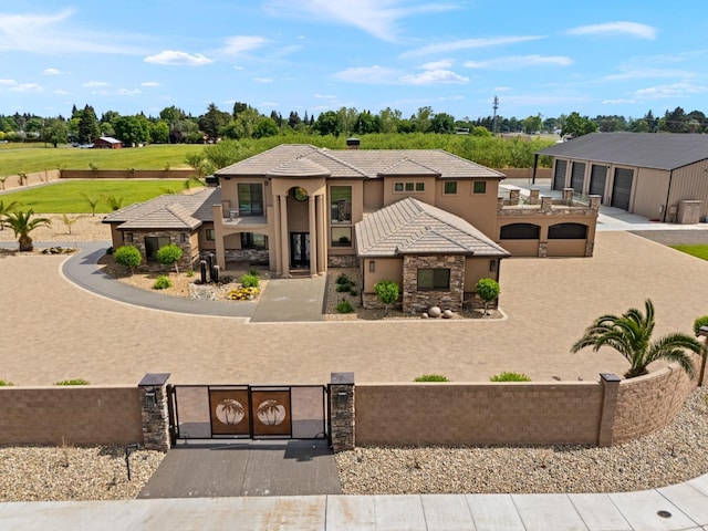 view of front facade with a fenced front yard, a tile roof, a gate, stone siding, and stucco siding