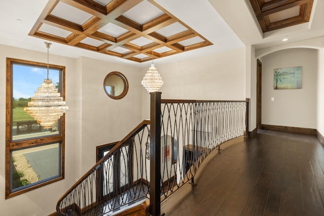 hall featuring arched walkways, coffered ceiling, dark wood-style flooring, and a notable chandelier