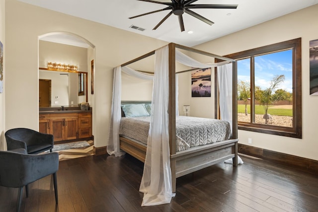 bedroom with visible vents, dark wood finished floors, a sink, baseboards, and connected bathroom