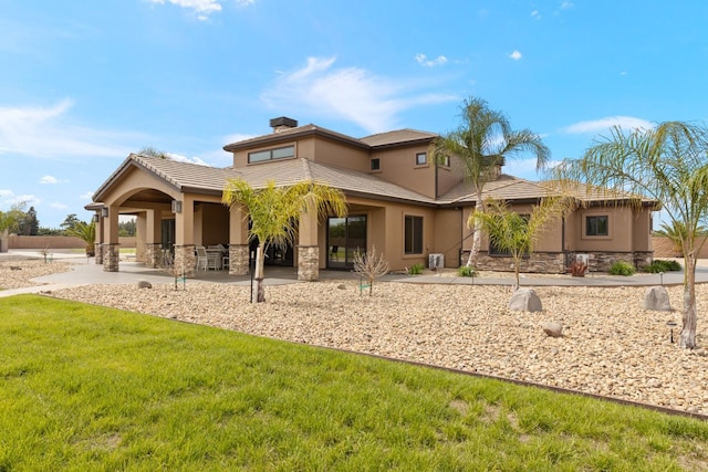 back of property featuring stone siding, stucco siding, a chimney, a patio area, and a yard