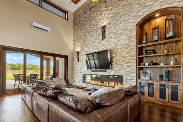 living area featuring a fireplace, an AC wall unit, hardwood / wood-style flooring, and a towering ceiling