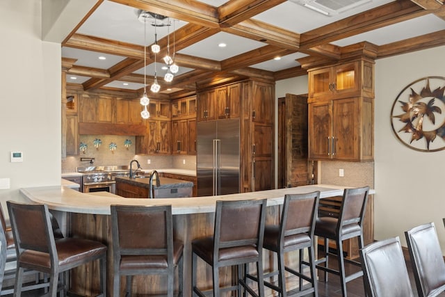 kitchen featuring light countertops, a peninsula, high end appliances, visible vents, and coffered ceiling