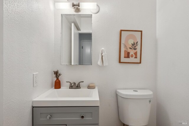 half bathroom with toilet and vanity