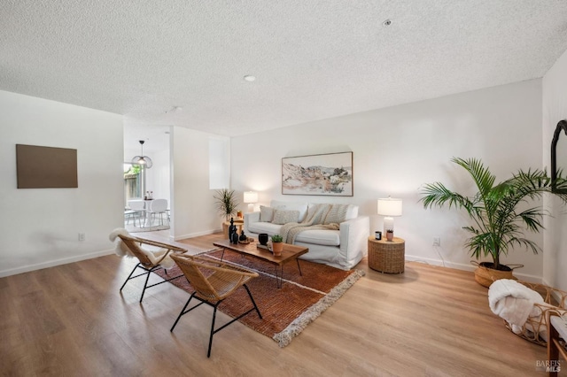 living area with baseboards, a textured ceiling, and wood finished floors