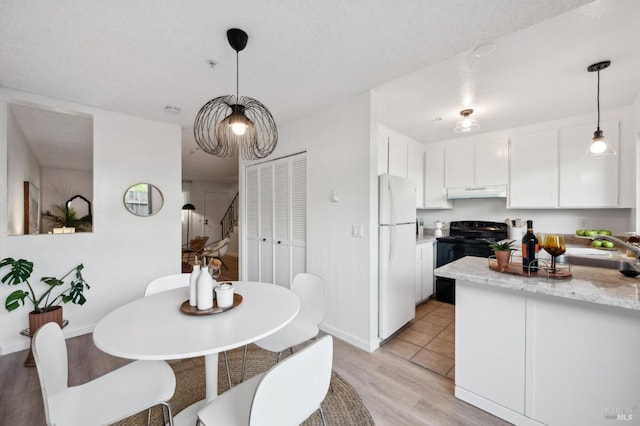 kitchen with light wood finished floors, freestanding refrigerator, white cabinetry, black range with electric cooktop, and under cabinet range hood