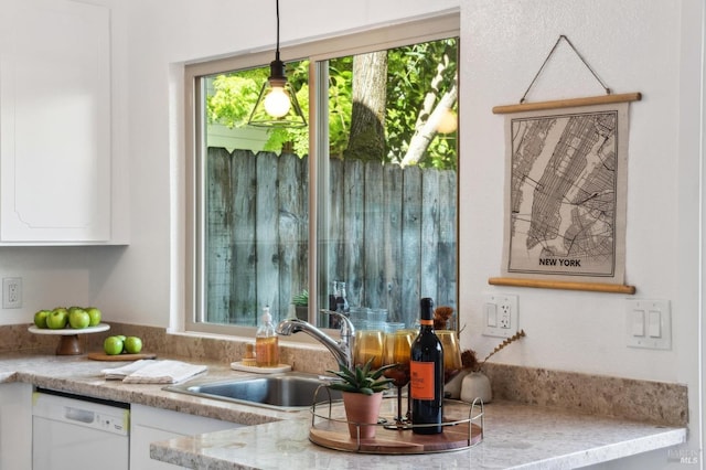 interior space with decorative light fixtures, white dishwasher, light stone countertops, a sink, and white cabinetry