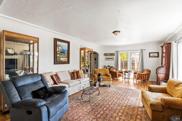 living room with crown molding, arched walkways, a textured ceiling, and wood finished floors