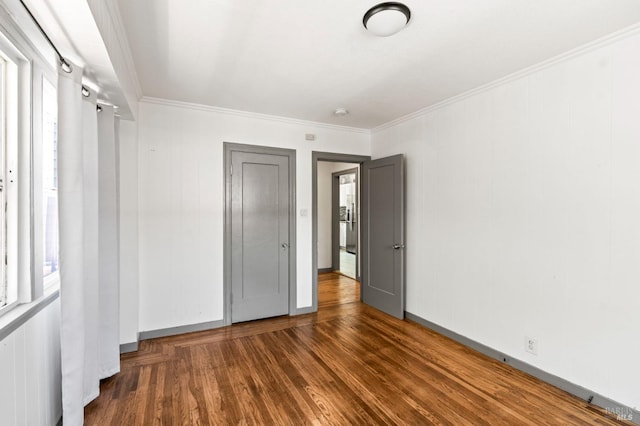 unfurnished bedroom with ornamental molding, wood finished floors, and multiple windows