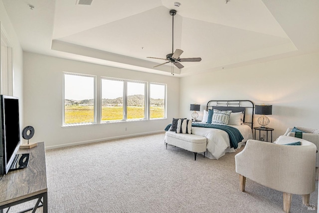 carpeted bedroom with a raised ceiling, baseboards, a ceiling fan, and visible vents