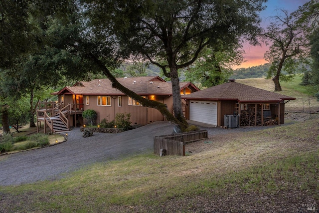 view of front of property with a deck, an attached garage, central air condition unit, driveway, and stairway