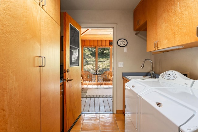 laundry area with a sink, separate washer and dryer, light tile patterned floors, and cabinet space
