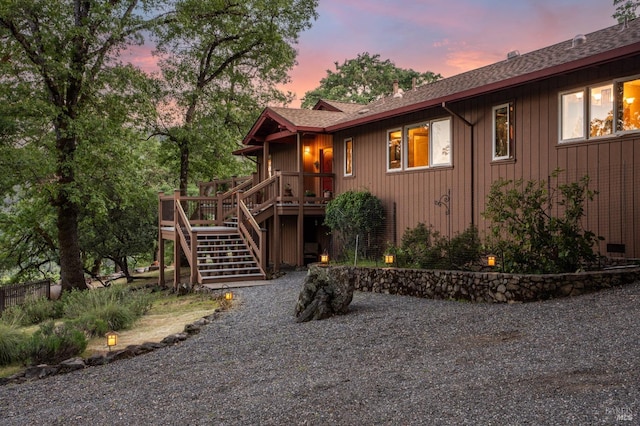 rustic home with a shingled roof, stairway, and a deck