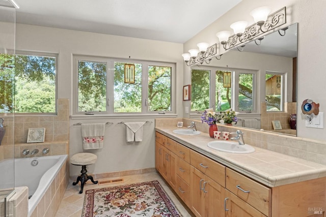full bathroom featuring double vanity, a relaxing tiled tub, tile patterned floors, and a sink