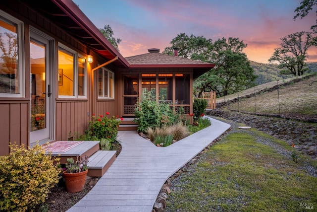 exterior space featuring fence, board and batten siding, and a shingled roof