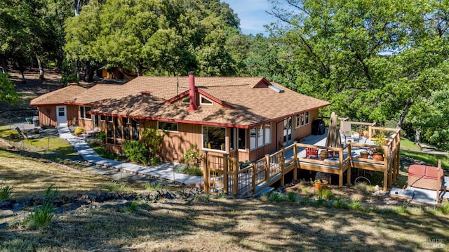 rear view of house featuring a wooden deck, a shingled roof, and a wooded view