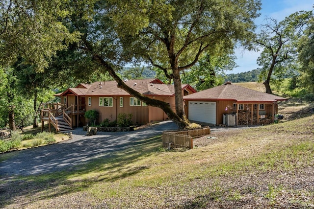 ranch-style home with stairs, an attached garage, central AC unit, and driveway