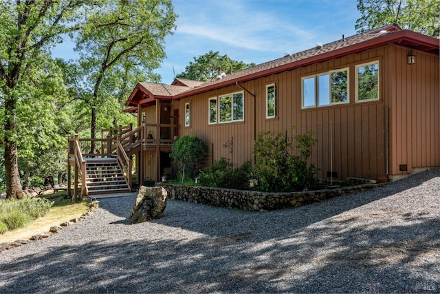 view of side of home featuring stairs, roof with shingles, and a wooden deck