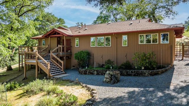 back of property featuring stairs, roof with shingles, and a wooden deck