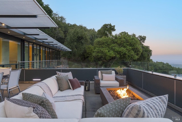 patio terrace at dusk featuring an outdoor living space with a fire pit and a balcony