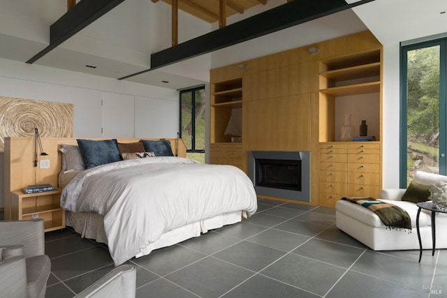 bedroom with dark tile patterned flooring, vaulted ceiling with beams, and a fireplace