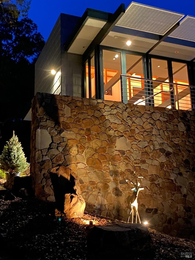 property exterior at night featuring stone siding