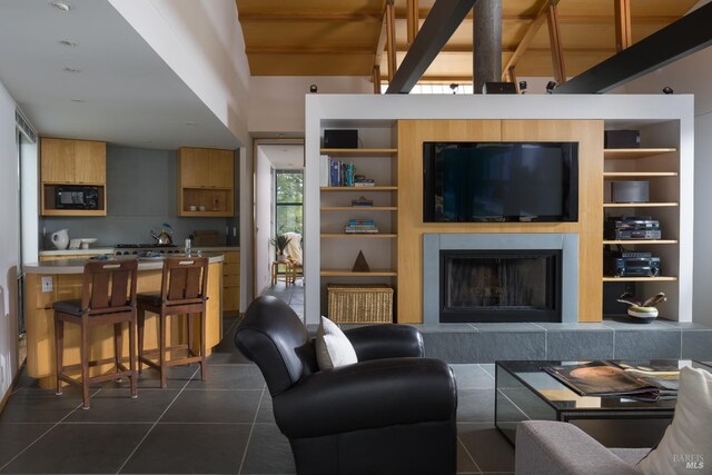 living room featuring dark tile patterned floors, a high ceiling, built in shelves, and a fireplace