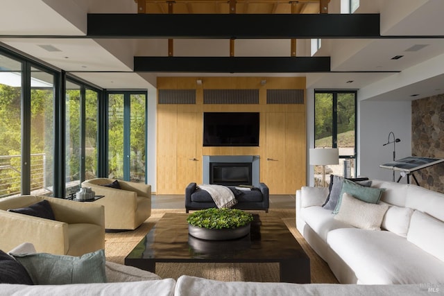 living area featuring expansive windows, a glass covered fireplace, and wood finished floors