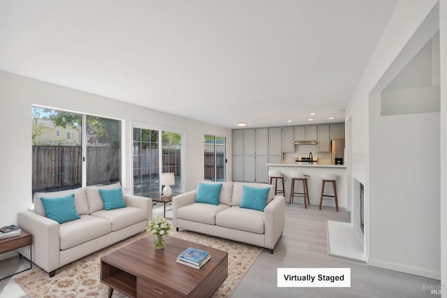 living area featuring recessed lighting, light wood finished floors, and baseboards