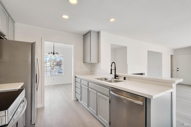 kitchen with a sink, stainless steel appliances, recessed lighting, light wood-type flooring, and gray cabinetry