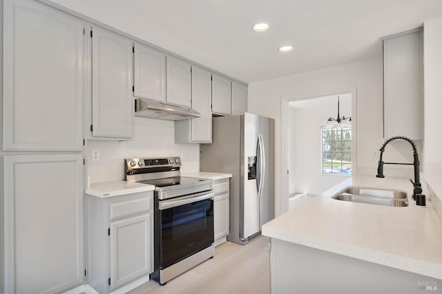 kitchen featuring appliances with stainless steel finishes, a sink, light wood-style floors, under cabinet range hood, and recessed lighting