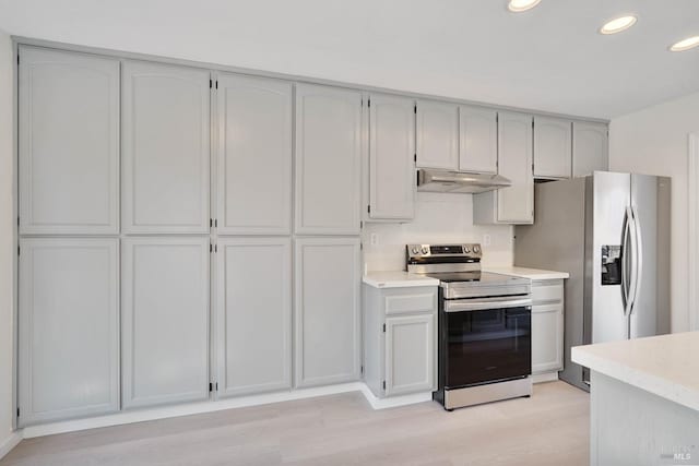 kitchen featuring light countertops, light wood finished floors, under cabinet range hood, stainless steel appliances, and recessed lighting