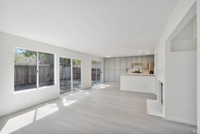 unfurnished living room with light wood-type flooring, recessed lighting, baseboards, and visible vents